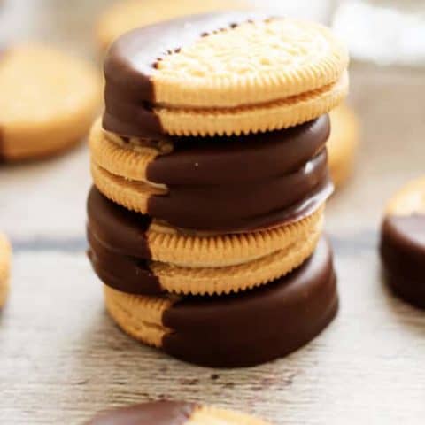 Stack of golden oreo cookies half dipped in melted chocolate.