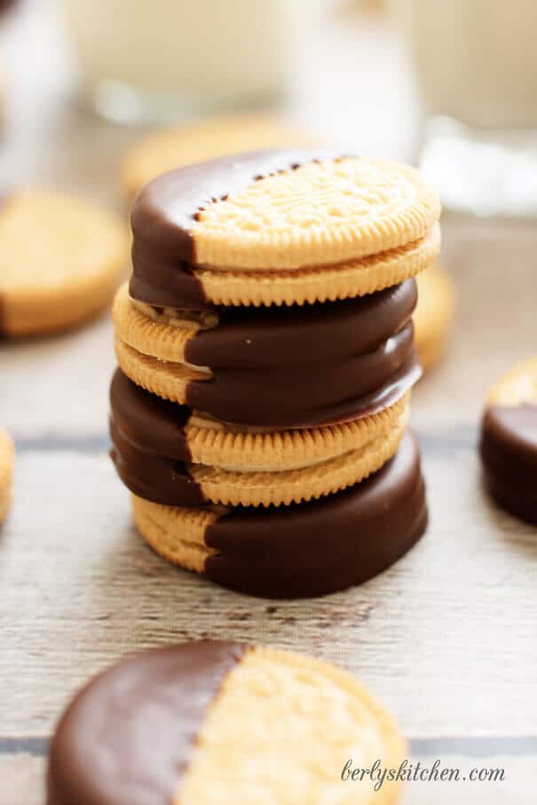 Stack of golden Oreo cookies half dipped in melted chocolate.