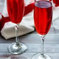 Two glasses of champagne in long stemmed wine glasses with a red ribbon.