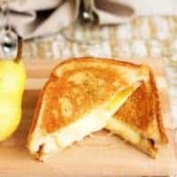 Two pieces of grilled cheese on a cutting board.