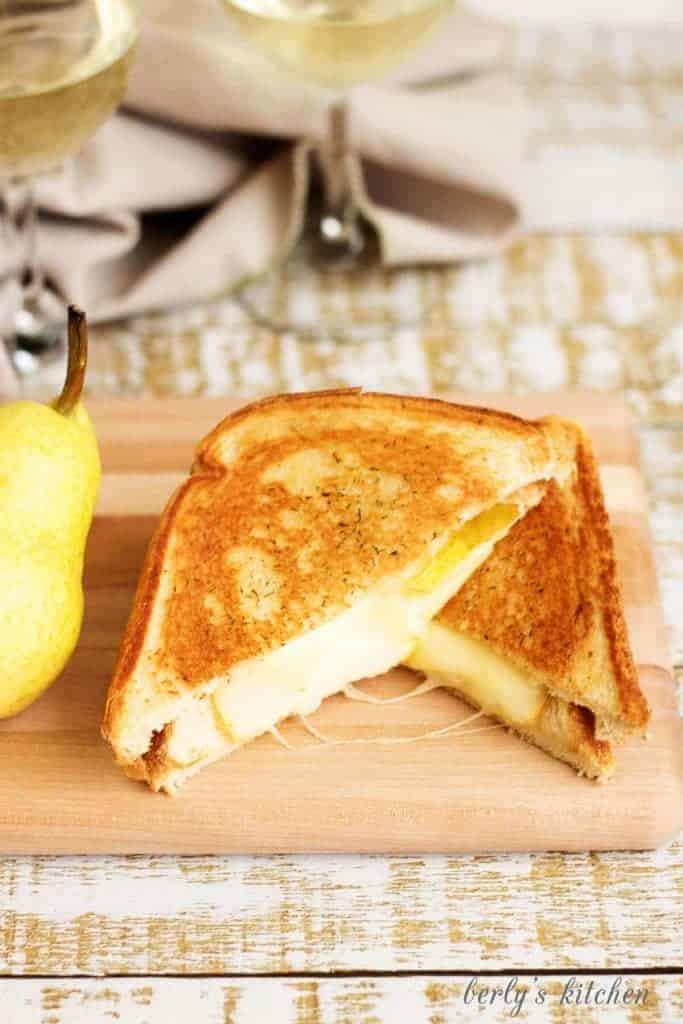 Two pieces of grilled cheese on a cutting board.