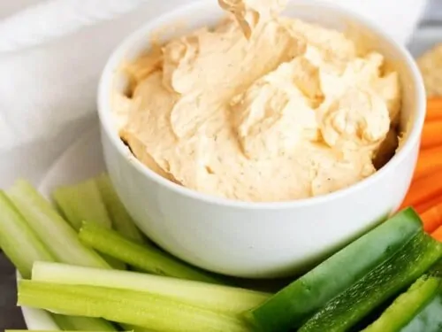 Cracker being dipped into buffalo cheese dip.