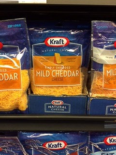 Packages of cheddar cheese on a store shelf.