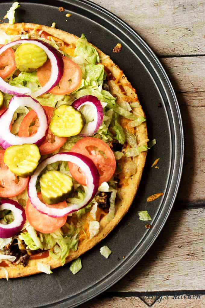 The Works Cheeseburger Pizza is a simple to prepare recipe loaded with all the fixings, including lettuce, tomatoes, pickles, and onions.
