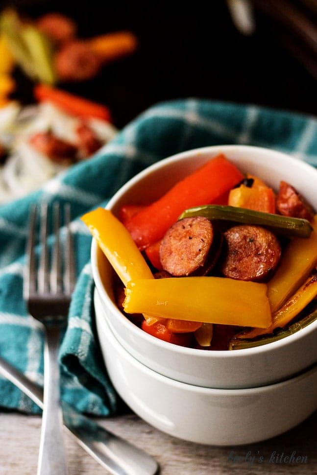 Sausage and peppers in a white bowl with forks.