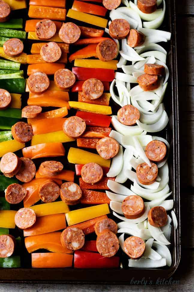 Spicy sausage and peppers in rows on a baking sheet.