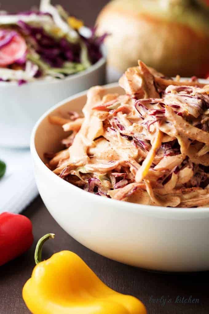Spicy coleslaw recipe in a white bowl with peppers.