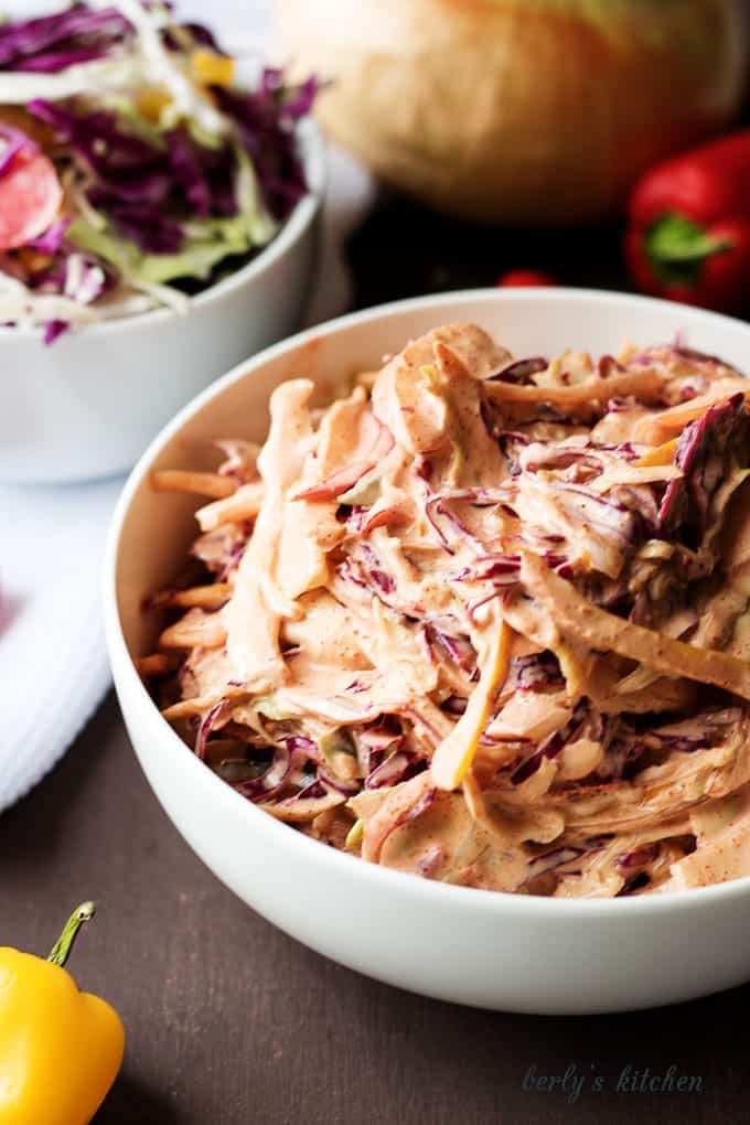 Spicy coleslaw recipe with a yellow pepper outside the bowl.