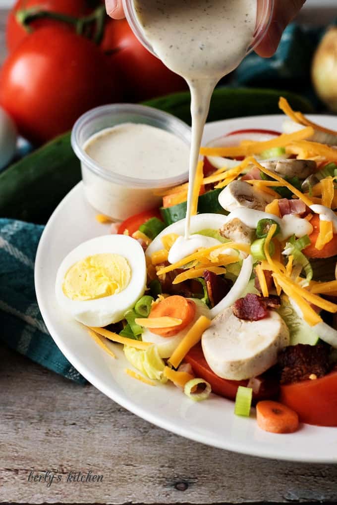 Chef salad with ranch dressing being poured on top.