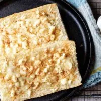 Feta mozzarella topped cheesy bread is the ultimate compliment or starter to any meal. We took Cuban bread, then topped it with feta, mozzarella, and garlic.