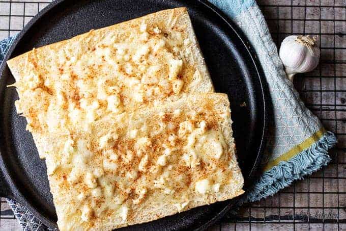 Feta mozzarella topped cheesy bread on cast iron.