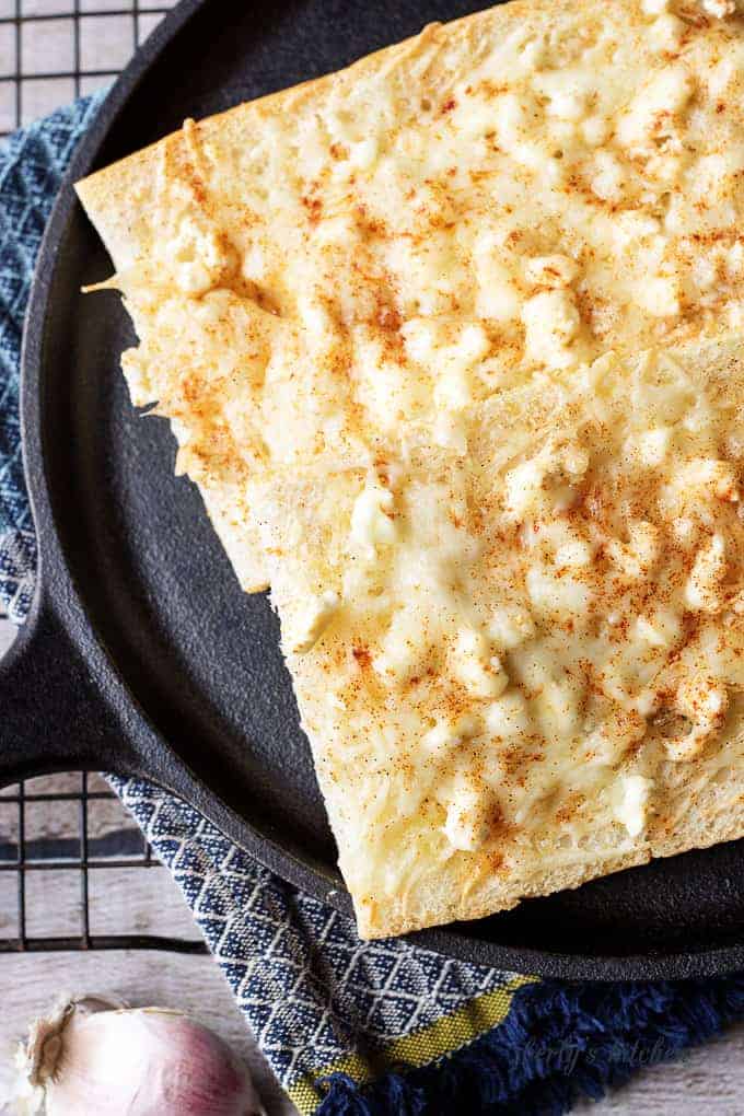 Top down view of feta mozzarella topped cheesy bread on a skillet.