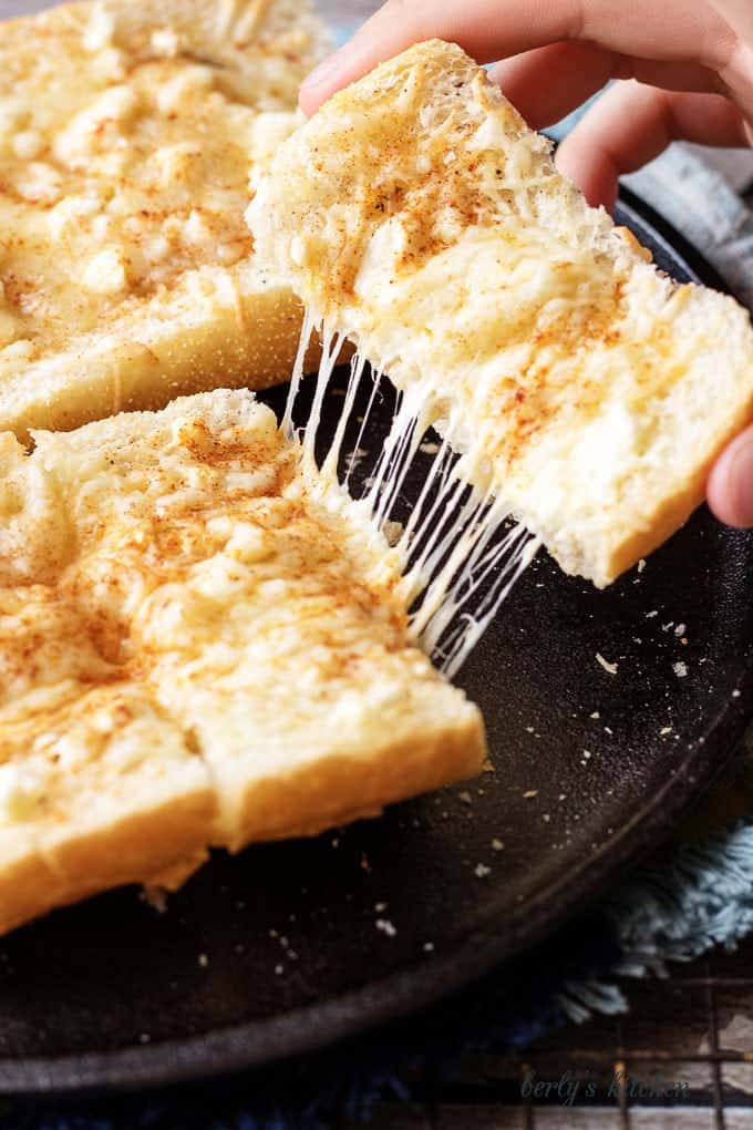 Feta mozzarella topped cheesy bread with cheese being stretched.