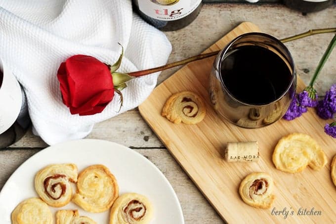 Crackers, rose, and glass of wine on a cutting board.