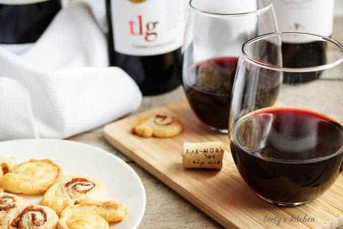  Two glasses of red wine on a cutting board with crackers.