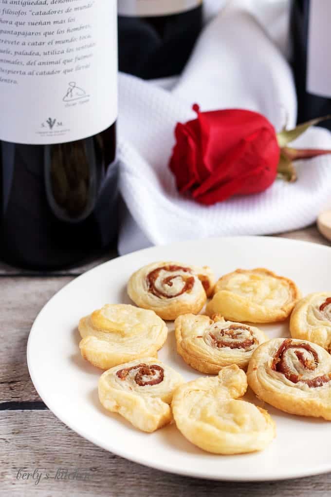 Appetizer crackers on a white plate with a red rose.