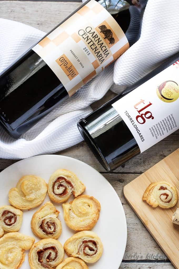 Top down view of two bottles of wine and crackers on a white plate.