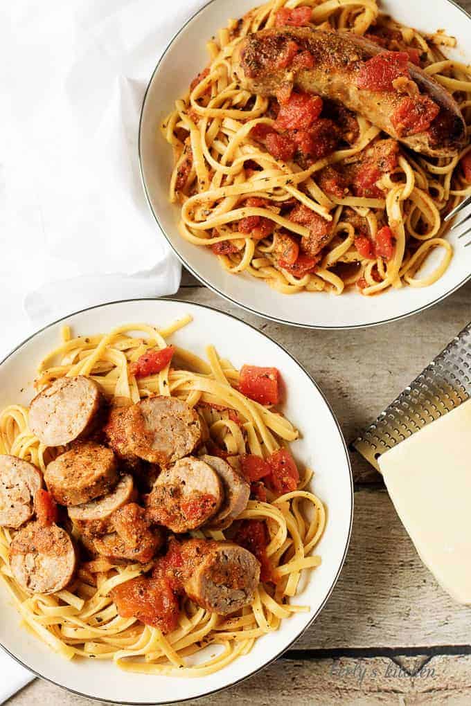 Top down view of two bowls of sausage linguine with parmesan cheese.