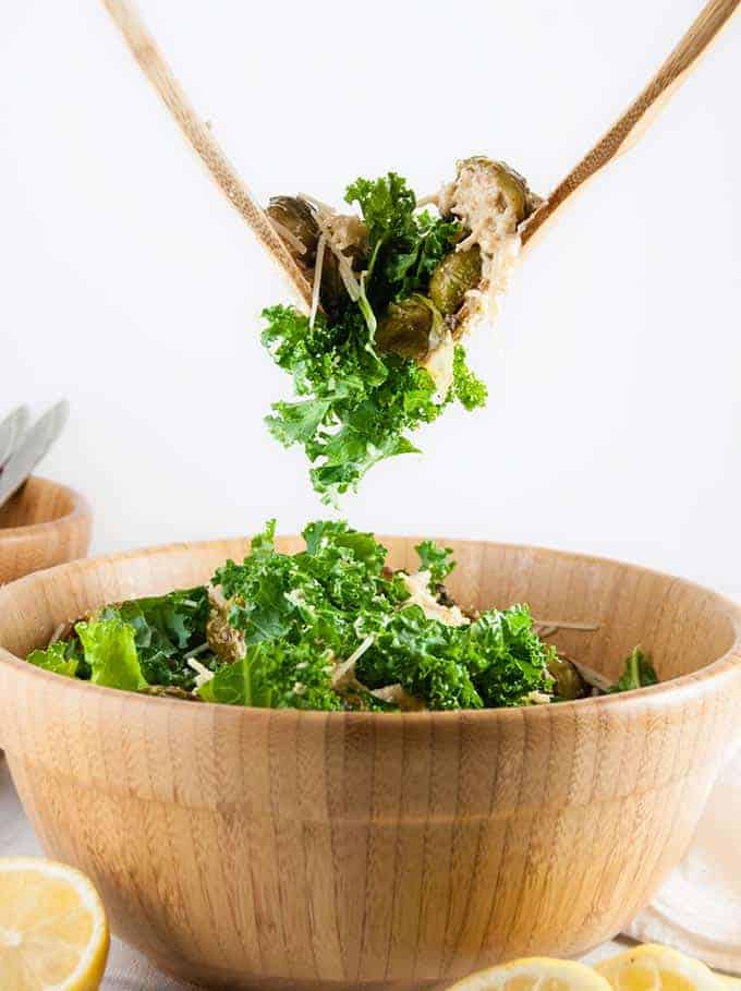 Brussels sprouts salad being tossed with wooden spoons.