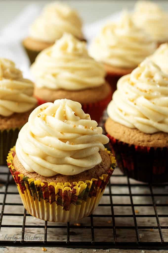 Multiple frosted cupcakes on a cooling rack.