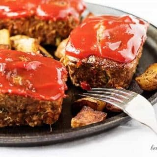 Mini meatloaves topped with ketchup next to two forks.