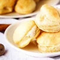 Cream puffs stacked on plate next to fresh nutmeg and cinnamon stick.