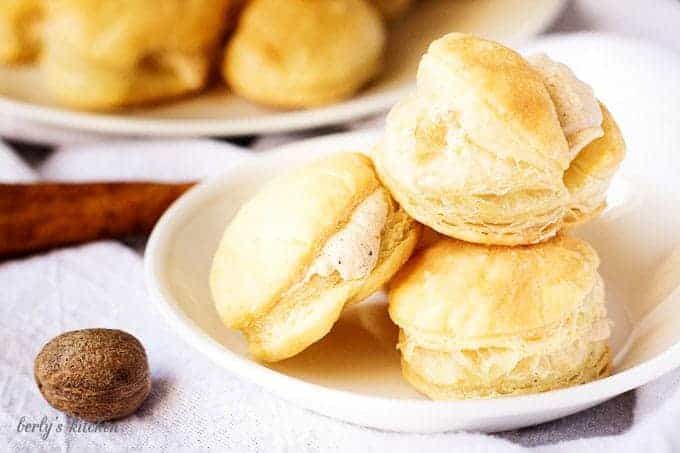 Cream puffs stacked on plate next to fresh nutmeg and cinnamon stick.