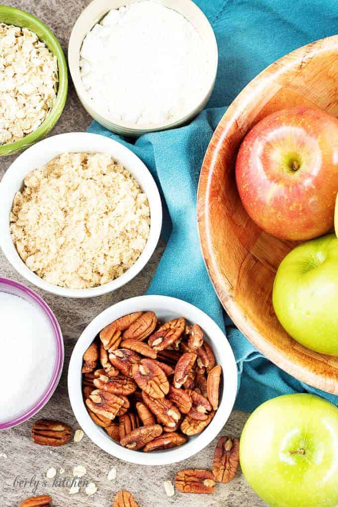 A top-down view of the ingredients, apples, pecans, flour, butter in bowls.