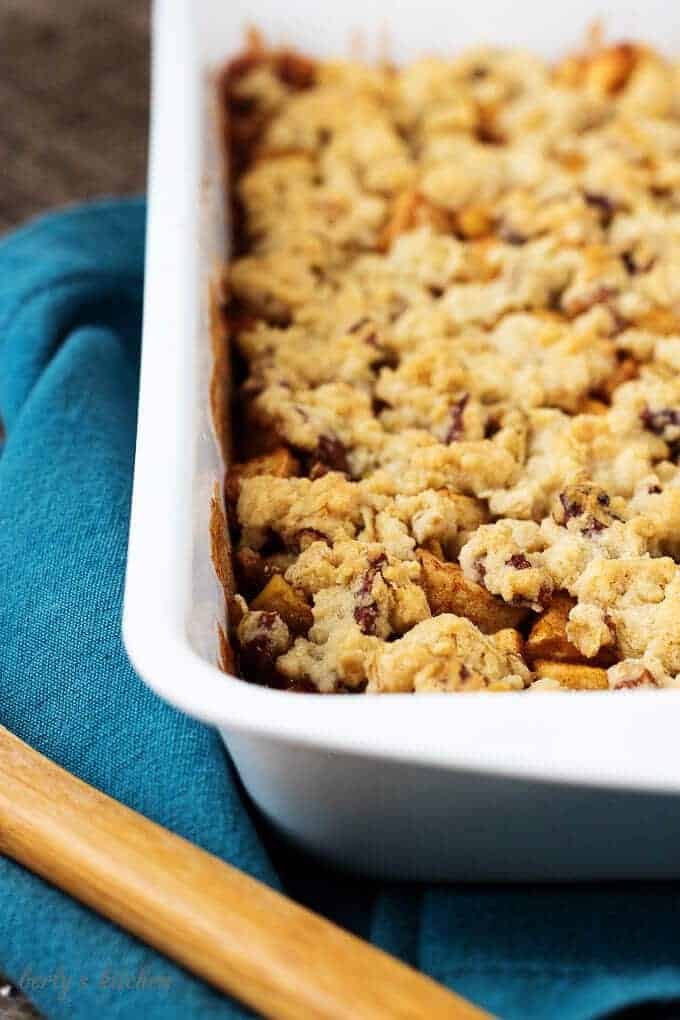 An angled view of the cooked apple crisp in a baking dish on a blue towel.