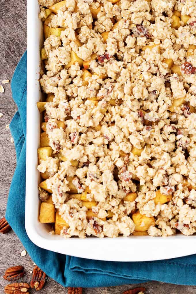 Top-down view of the prepped apple crisp in a white baking dish.