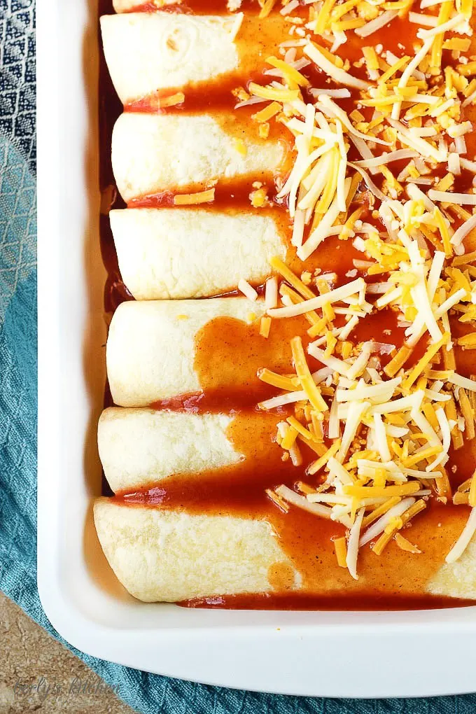 The prepped enchiladas smothered with sauce and shredded cheese blend.