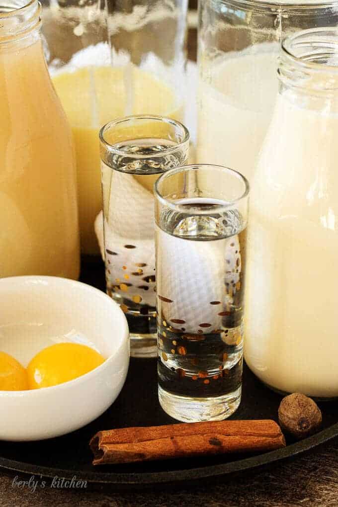 The coquito recipe ingredients, like white rum, egg yolks, and coconut cream in containers.