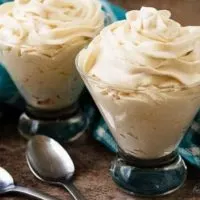 Two cocktail glasses with Irish Cream Flavored Whipped Cream and spoons.