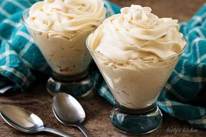 Two cocktail glasses with irish cream flavored whipped cream and spoons.