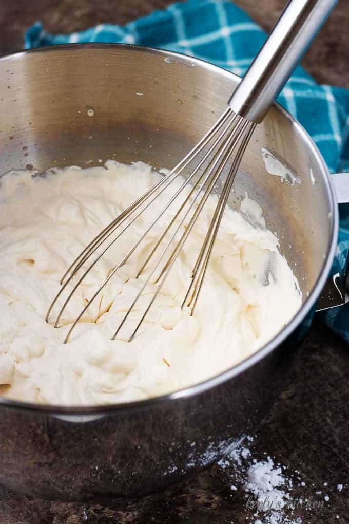 Irish cream flavored whipped cream with a metal whisk in a metal mixing bowl.