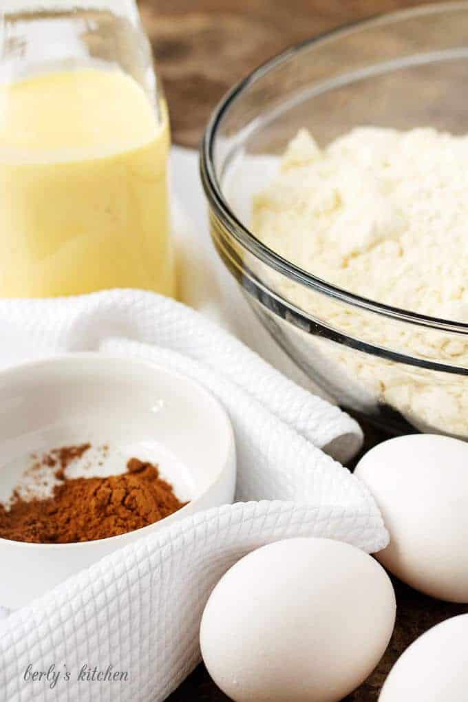 All the ingredients in bowls and dishes like eggs, spices, eggnog, and cake mix.