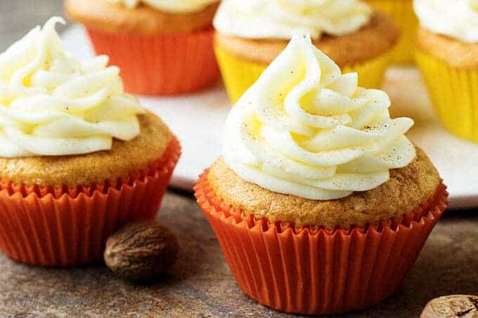 A close-up view of the finished eggnog cupcakes with buttercream frosting in red liners.