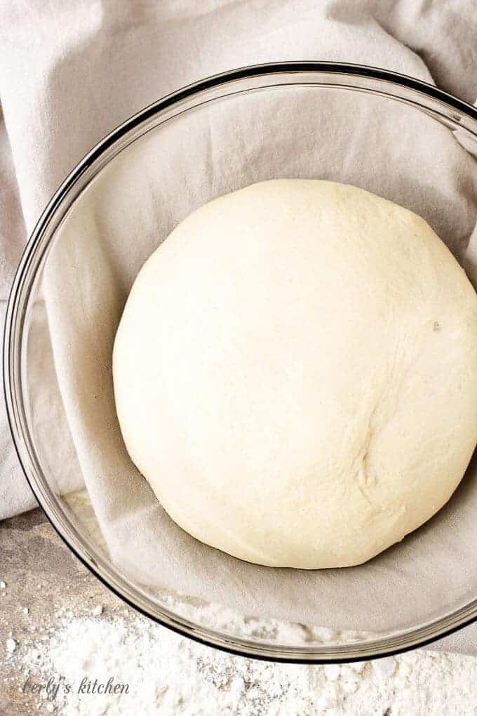 The ball of dough in a mixing bowl and has doubled in size after rising.