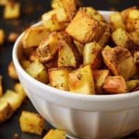 Oven-baked home fries in a white bowl on a sheet pan.