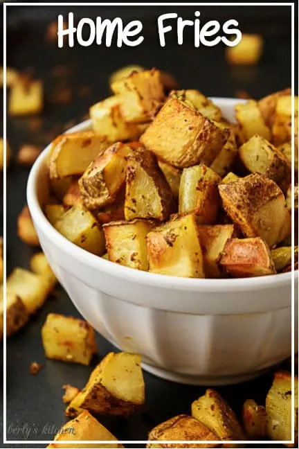 A close-up picture of the finished home fries recipes in a white bowl on a dark sheet pan.