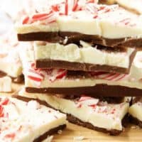 The cooled peppermint bark pieces, stacked up on a wooden cutting for serving.