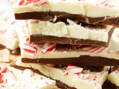The cooled peppermint bark pieces, stacked up on a wooden cutting for serving.