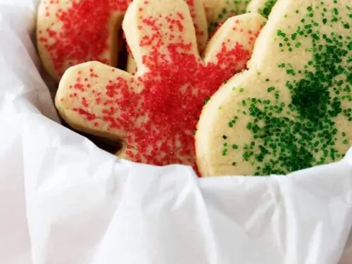 The colorful soft sugar cookies in cookie tine surrounded by decorative paper.