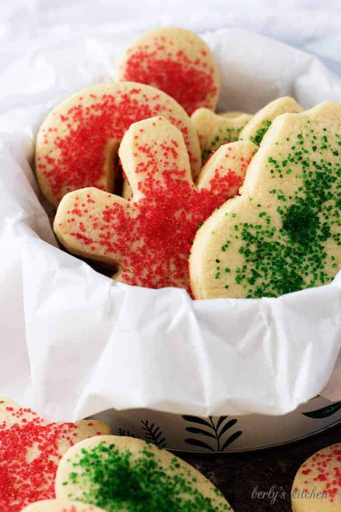 The colorful soft sugar cookies in cookie tine surrounded by decorative paper.