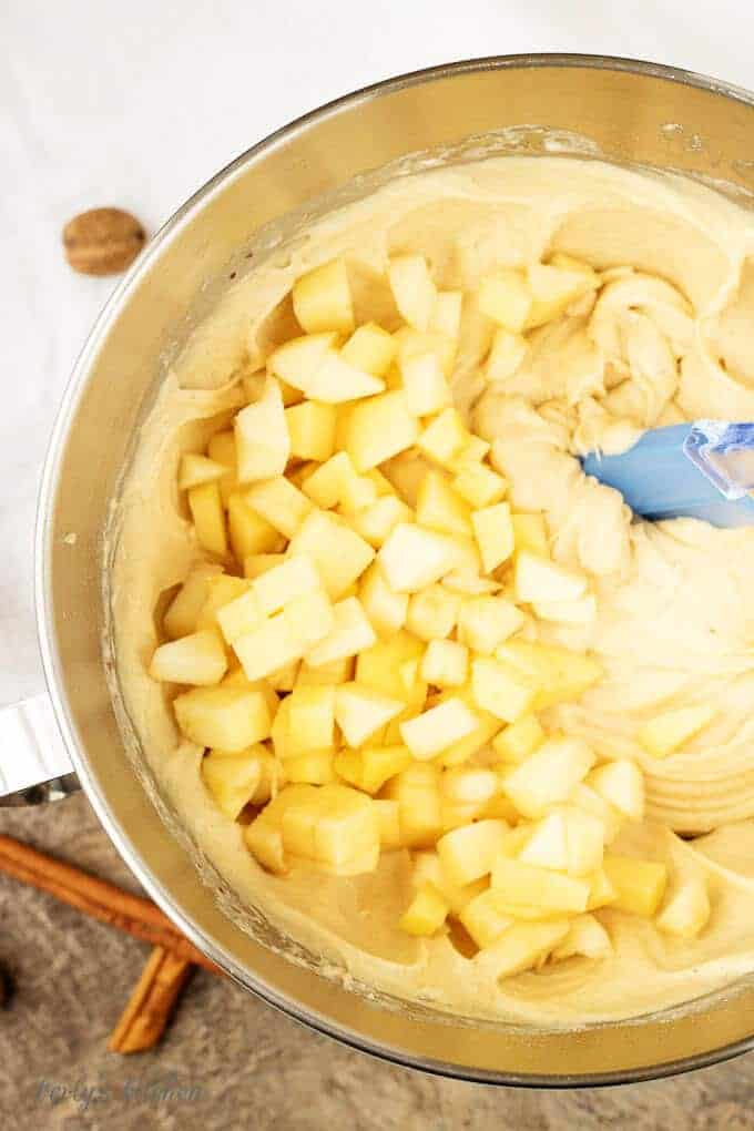A top -down view of the diced apples being folded into the apple cinnamon muffins batter.
