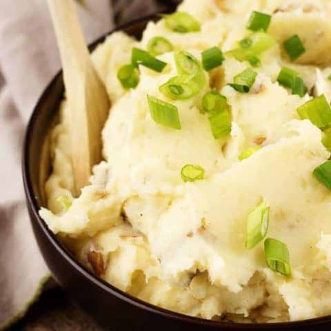 A close-up photo of the finished parmesan mashed potatoes in a brown serving bowl.