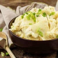 The finished Parmesan mashed potatoes in a serving bowl garnished with diced green onions.