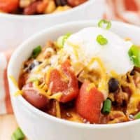 A close-up view of the three bean chili garnished with cheese and green onions.