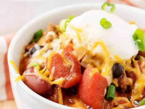 A close-up view of the three bean chili garnished with cheese and green onions.