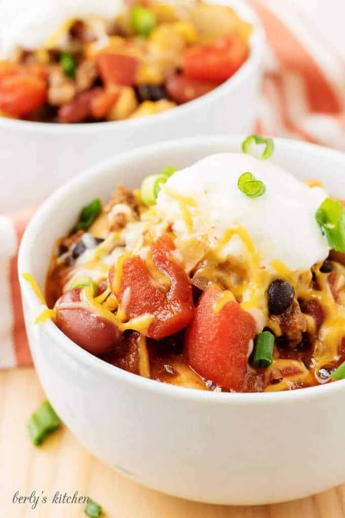 A close-up view of the three bean chili garnished with cheese and green onions.